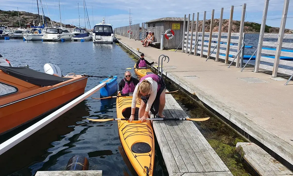 Förberedelser för kajakpaddling i Lysekil. En gul kajak ligger i vattnet vid en brygga, redo för äventyr.