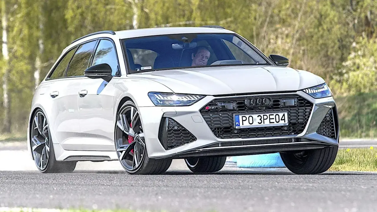Białe Audi RS6 Avant na torze, kierowca wpatrzony przed siebie.