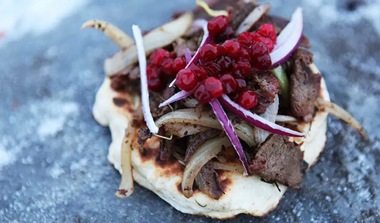 En smak av samisk mat: tunnbröd med renkött, stekt lök och lingon.