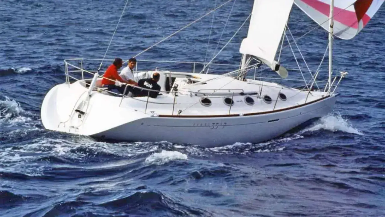 Voilier blanc naviguant sur une mer agitée. Trois personnes à bord. Le numéro 3517 est visible sur la coque.