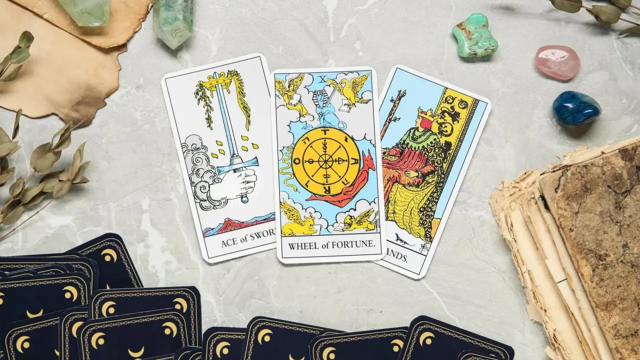 Karta życia tarot: As Mieczy, Koło Fortuny i Król Buław. Tajemnicze kryształy i stare księgi dopełniają mistyczną atmosferę.
