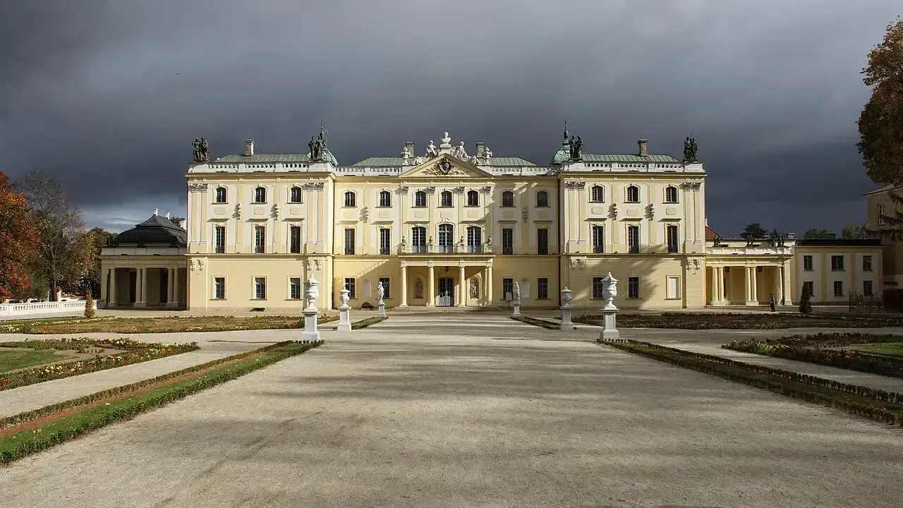 Pałac Branickich w Białymstoku, majestatyczna budowla z ogrodem, pod burzowym niebem.