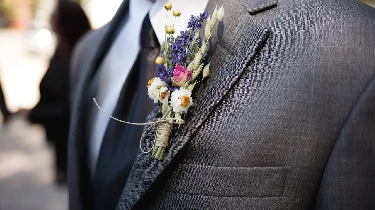 Brat weselny w garniturze, ozdobiony bukiecikiem suszonych kwiatów. Widać, kto jest kim w weselu dzięki jego eleganckiemu wyglądowi.