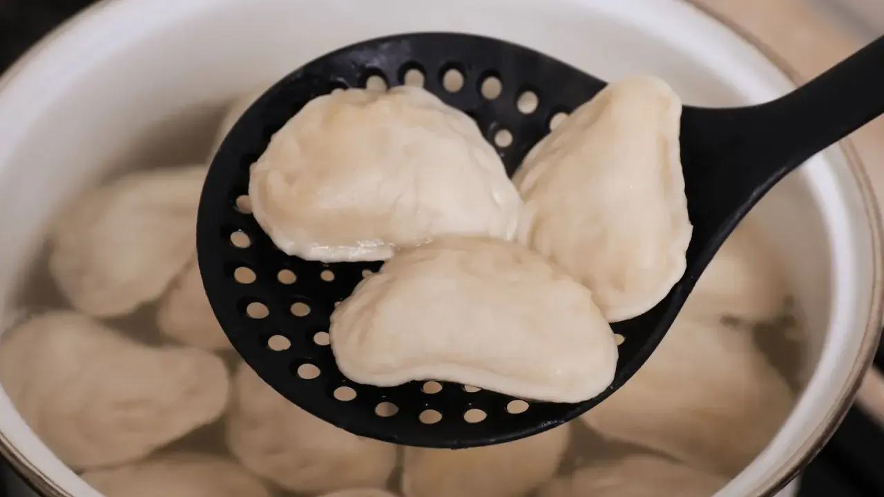 Gotowanie mrożonych pierogów: wyjęte z wrzątku na cedzaku, gotowe do podania.