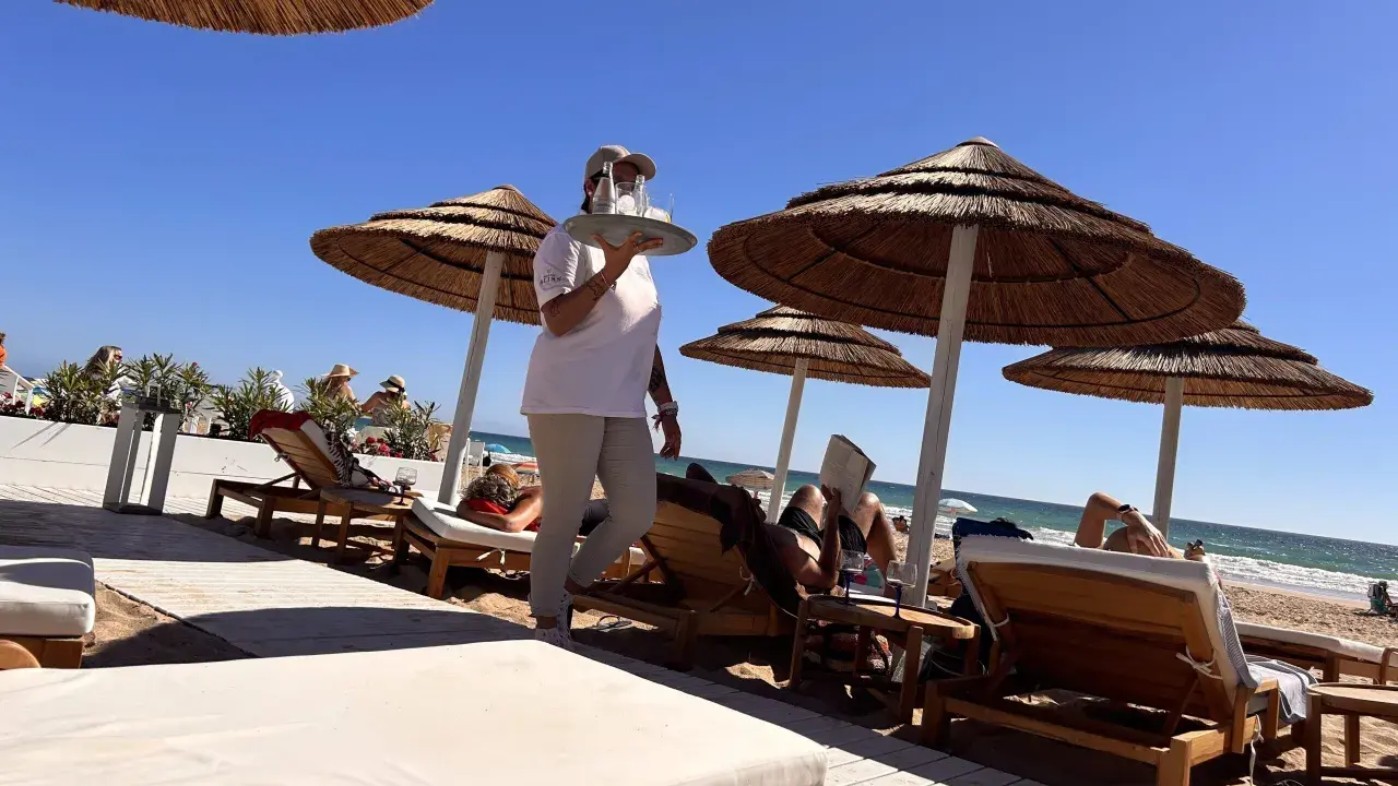 Kellnerin bringt Getränke an Liegestühle am Strand. Perfekte Feiertage Spanien!