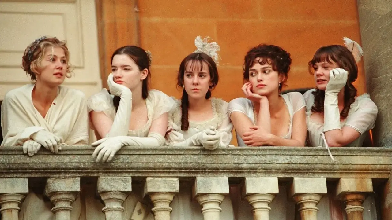 Cinque donne in abiti d'epoca, forse sorelle, riflettono su orgoglio e pregiudizio mentre guardano da un balcone.