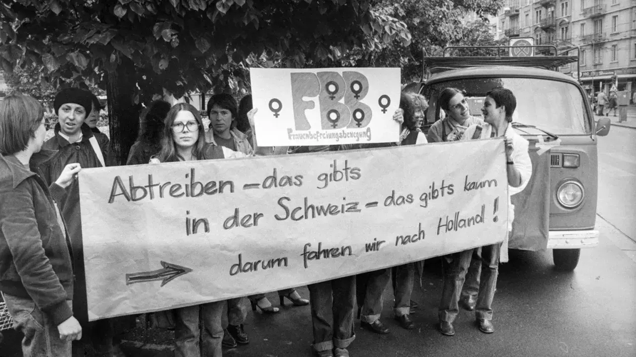 Frauen demonstrieren für das Recht auf Abtreibung. Die Botschaft "Abtreiben – das gibts in der Schweiz – das gibts kaum, darum fahren wir nach Holland!" zeigt eine frühe Welle des Feminismus.