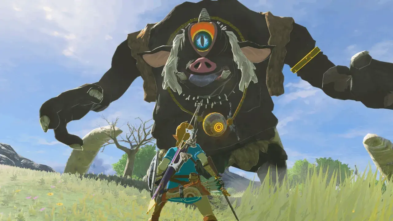 Link z gry Zelda Breath of the Wild staje naprzeciw gigantycznego Guardian'a na tle błękitnego nieba.