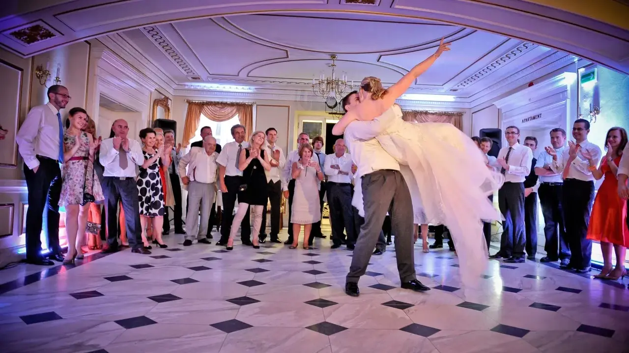 Para młoda wiruje w tańcu, goście patrzą z zachwytem. To piękny moment, jak bachata taniec.