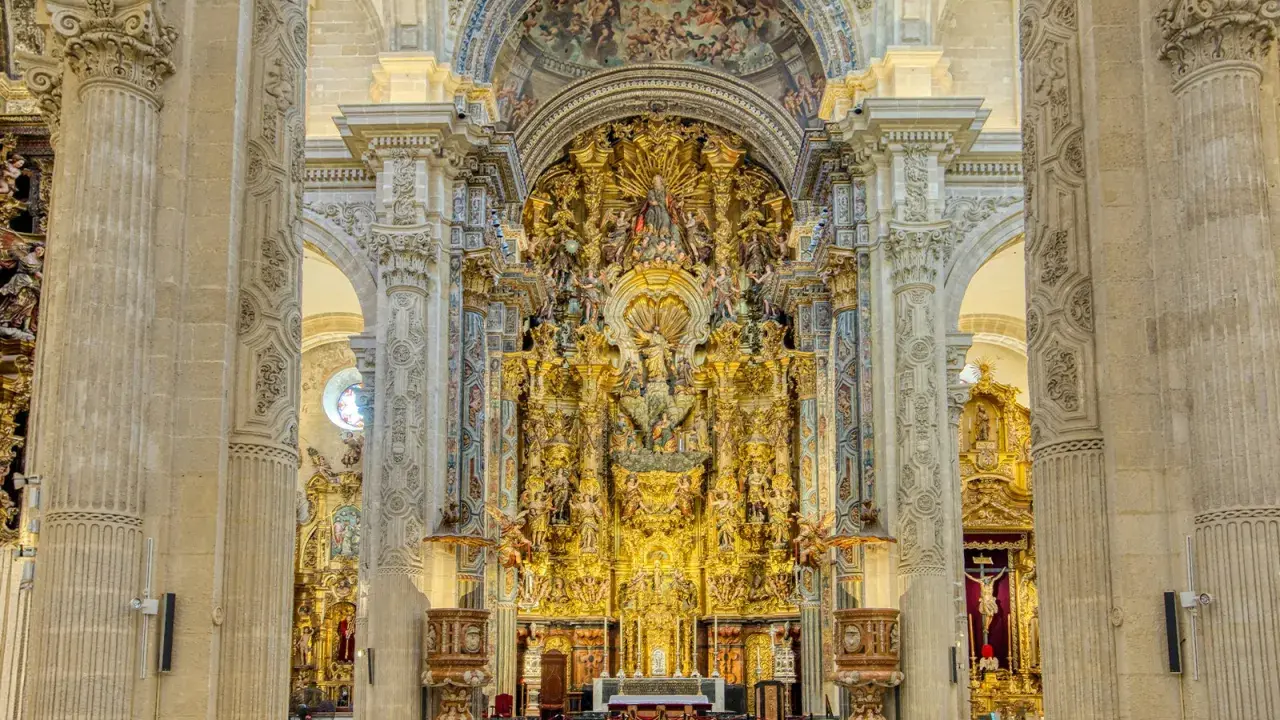 Prunkvoller Altar im Kathedrale Sevilla Innenraum, verziert mit goldenen Skulpturen und Malereien, die eine himmlische Szene darstellen.