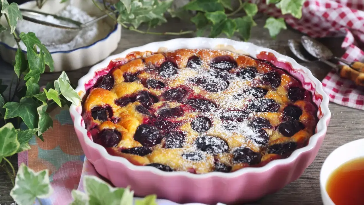 Un délicieux clafoutis aux prunes, saupoudré de sucre glace, prêt à être dégusté.