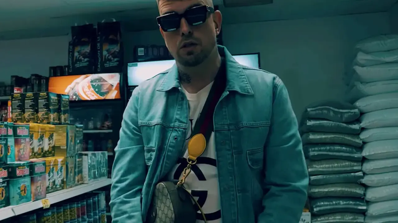 Malik Sentino w okularach i dżinsowej kurtce stoi w sklepie, otoczony towarem.