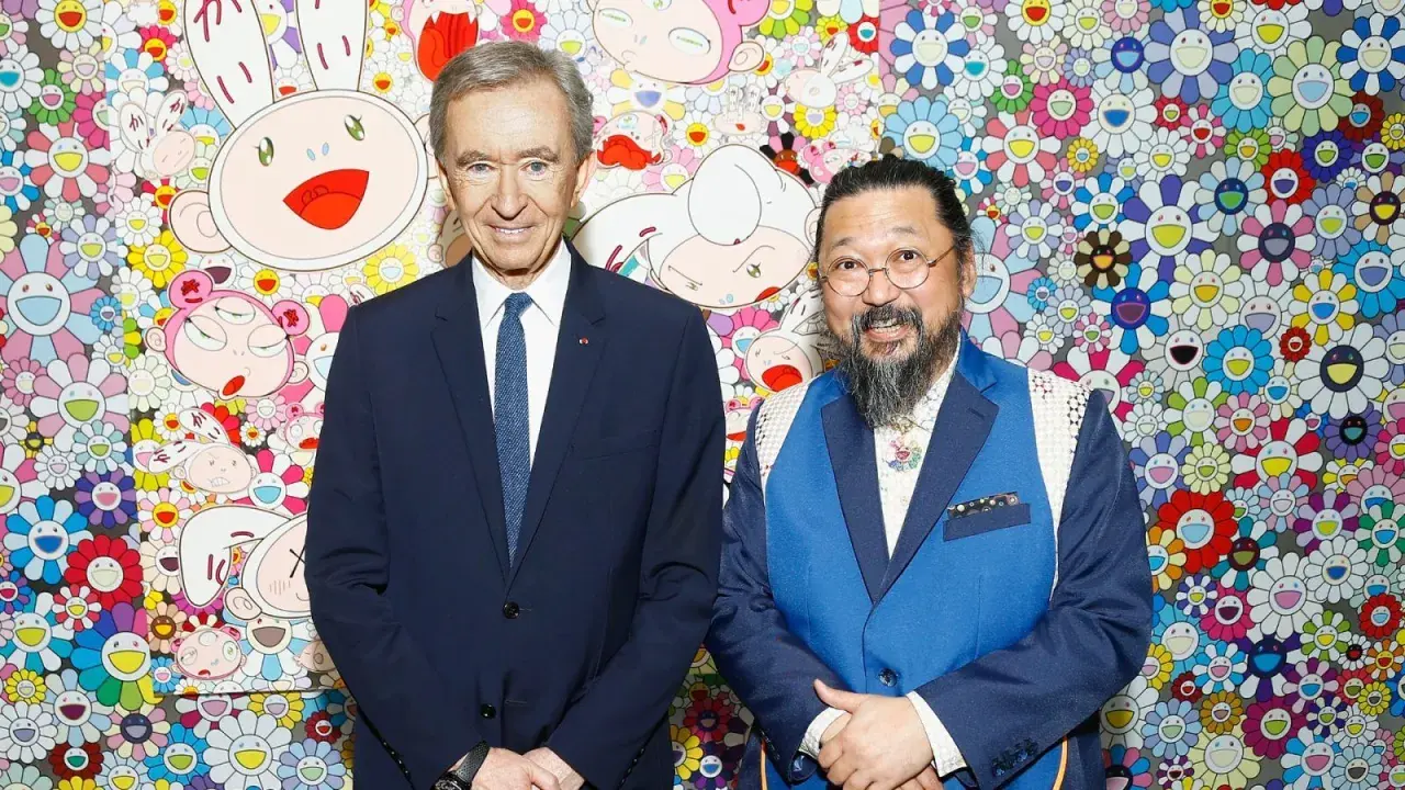 Two billionaire art collectors, Bernard Arnault and Takashi Murakami, pose in front of Murakami's signature smiling flower art.