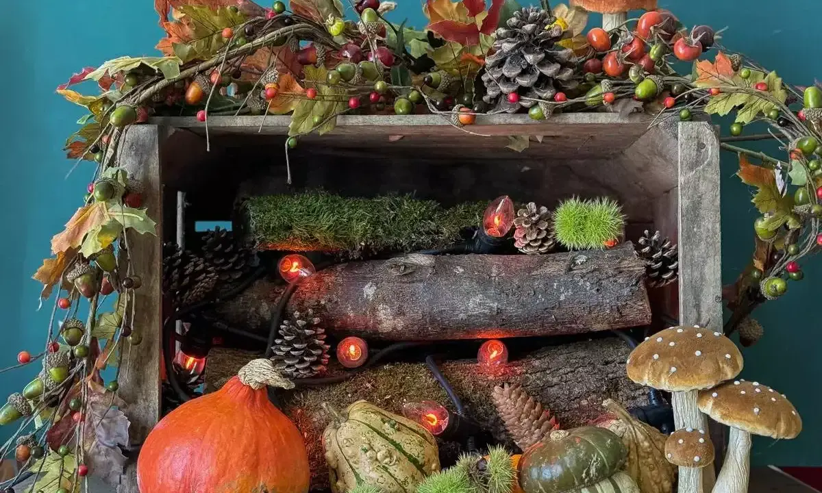 Décoration automne facile à faire : citrouilles, pommes de pin, guirlande de feuilles et champignons dans une caisse en bois.