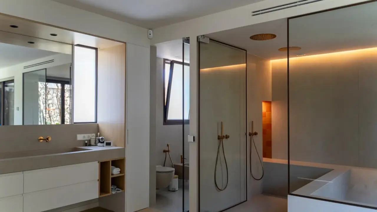 Moderno baño con ventana, ducha de cristal, bañera y lavabo doble.