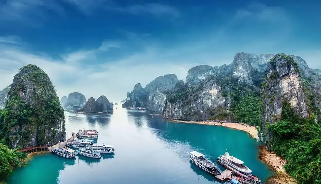 Widok na zatokę Ha Long w Wietnamie z łodziami i skalistymi wyspami.