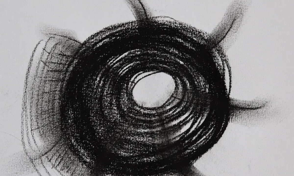Abstract charcoal mark making examples, featuring a dark, spiraling circle with radiating lines on a white background.