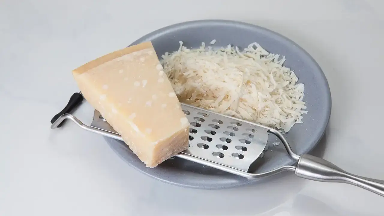 Kawałek sera i tarta masa na talerzu, obok tarka. Szukasz, czym zastąpić parmezan?