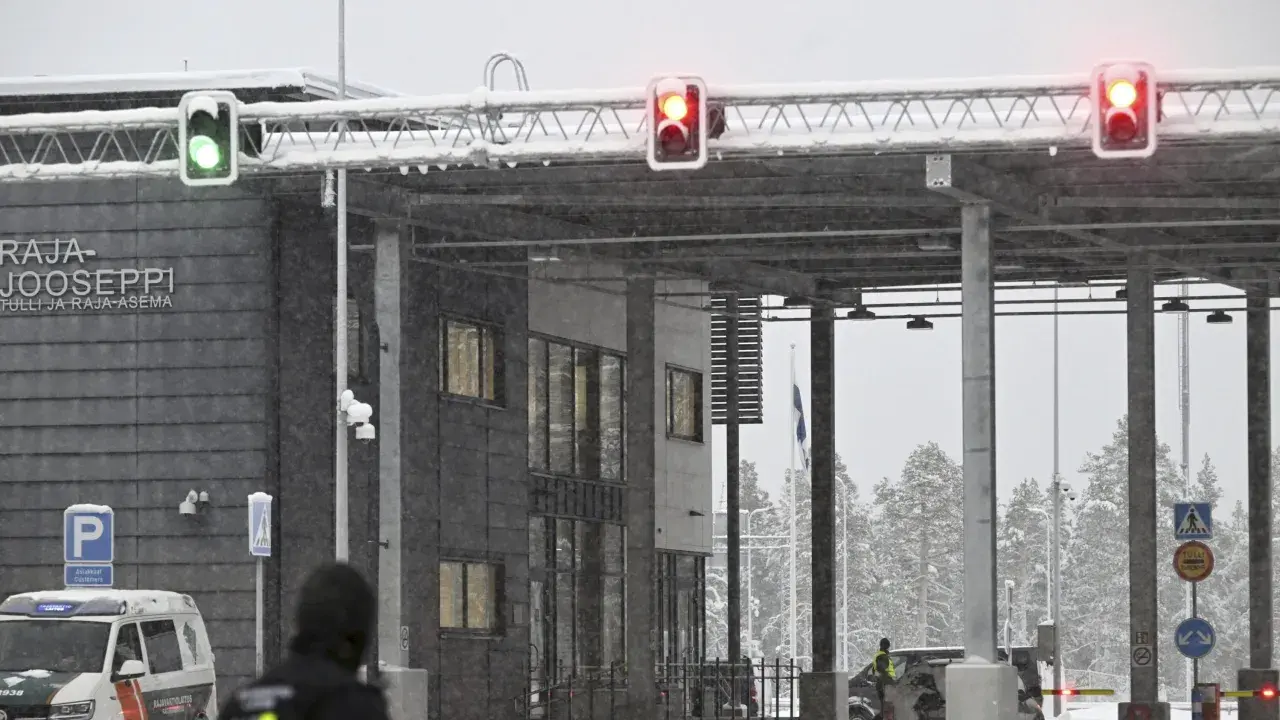 Grön trafiksignal vid gränsövergången Joensuu, Finland. Snö faller över byggnaden och träden. En polisbil syns. Gränsen mellan Ryssland och Finland är stängd.