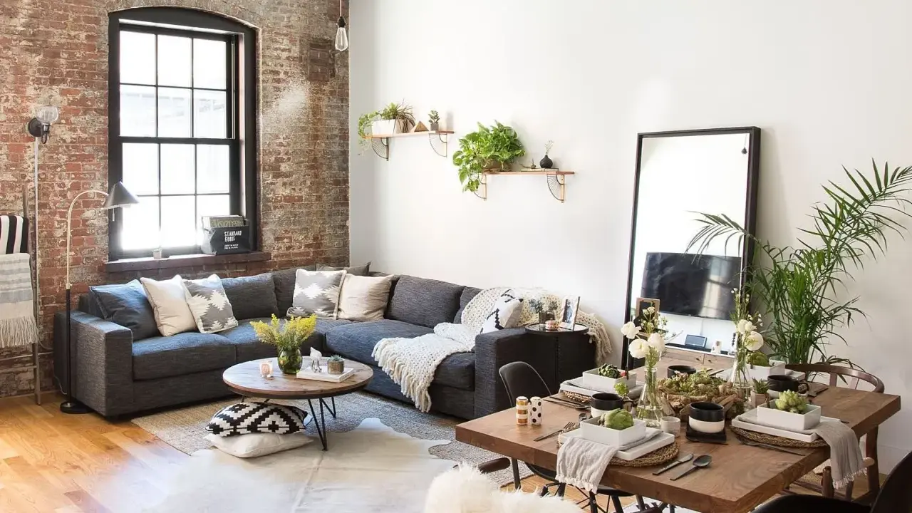 Sofá gris, mesa de centro redonda, mesa de comedor de madera y espejo de cuerpo entero crean un ambiente de **estilo cozy**.