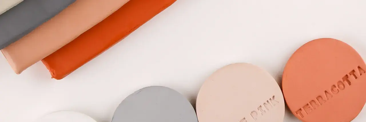 Stavar av lera som inte torkar i grått, rosa och orange, samt runda provbitar märkta "TERRACOTTA" och "ROSE PINK".