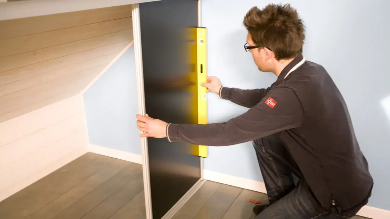 Un homme utilise un niveau pour fabriquer un placard sous pente de toit.