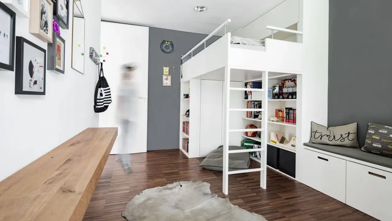 Ein weißes Hochbett mit integrierten Regalen und Stauraum bietet viele Ideen unterm Hochbett für Spielzeug und Bücher. Ein Holzbalken und ein Kuhfell-Teppich ergänzen den Raum.
