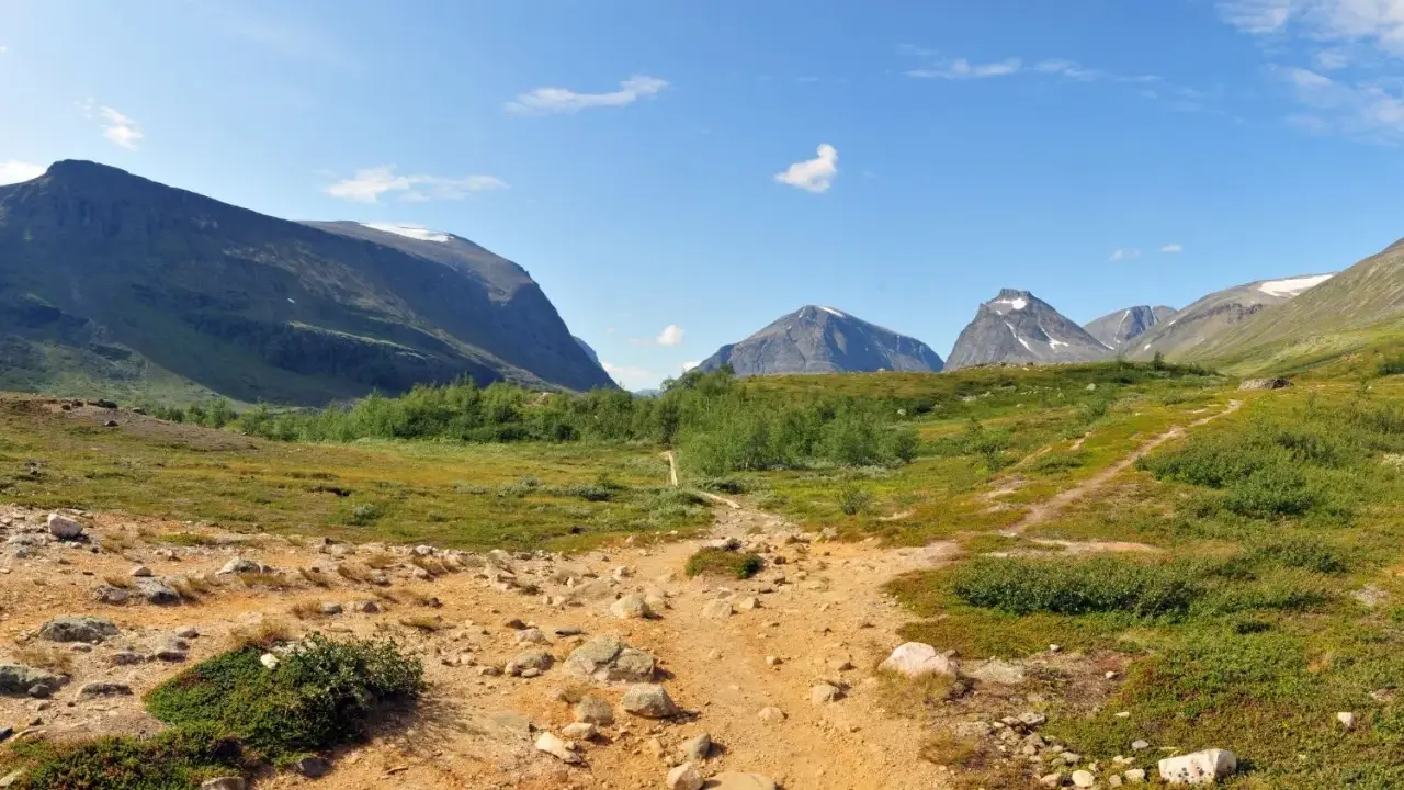 Vandringsled mot Kebnekaise, en fantastisk utsikt som gör bestiga Kebnekaise pris värt. Berg, grönska och en klarblå himmel.