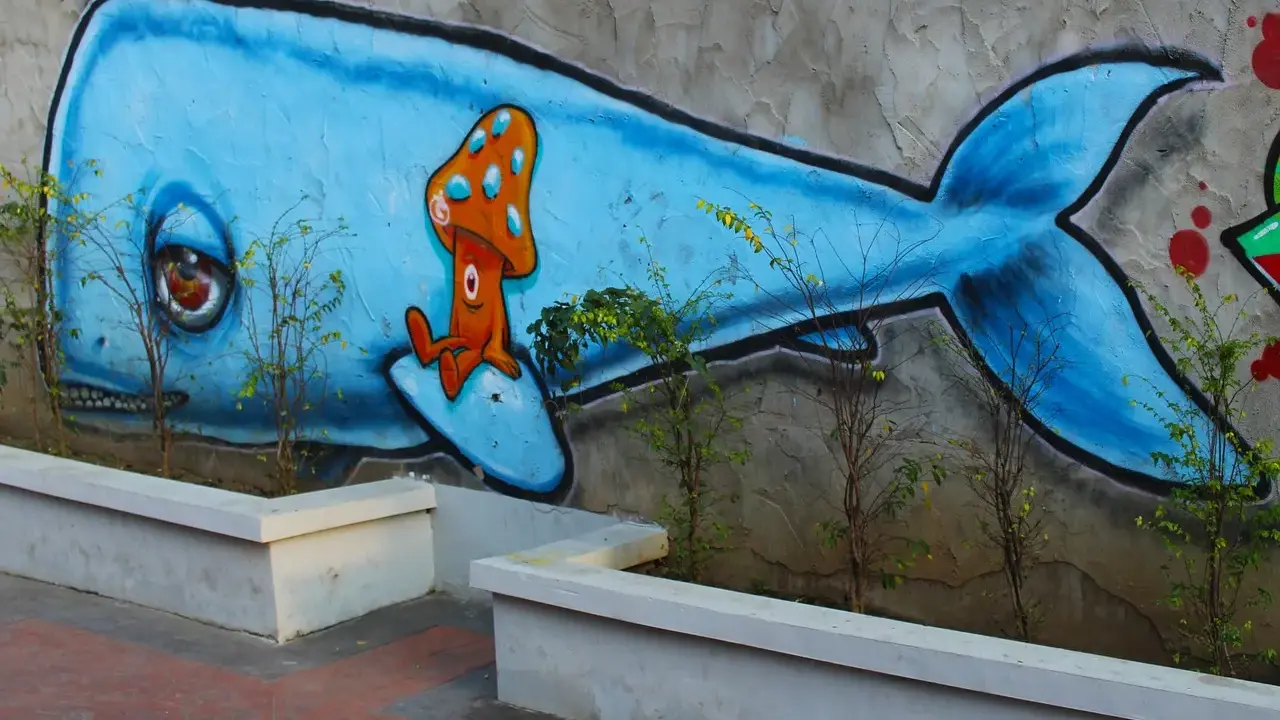 Niebieski wieloryb z grzybkiem na grzbiecie. Inspiracja, jak zrobić mural na kartce, w miejskim krajobrazie.