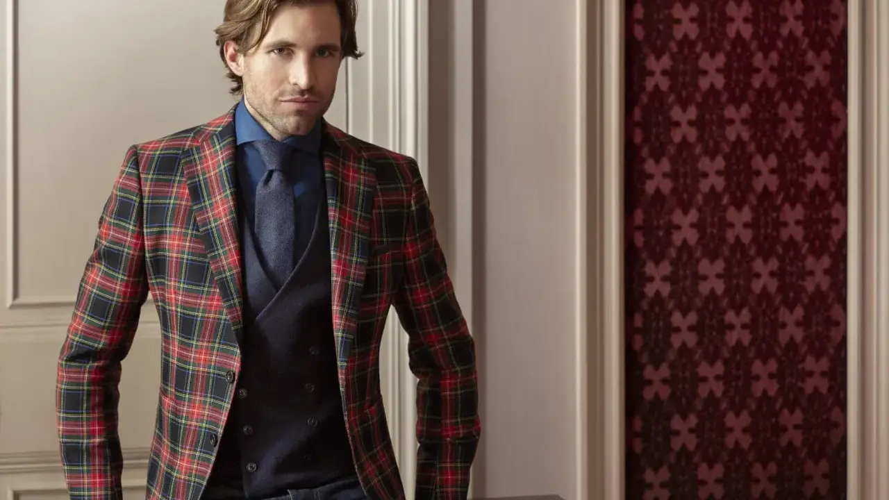 Man in a festive tartan blazer, dark blue shirt, tie, and vest. This is what holiday attire looks like.