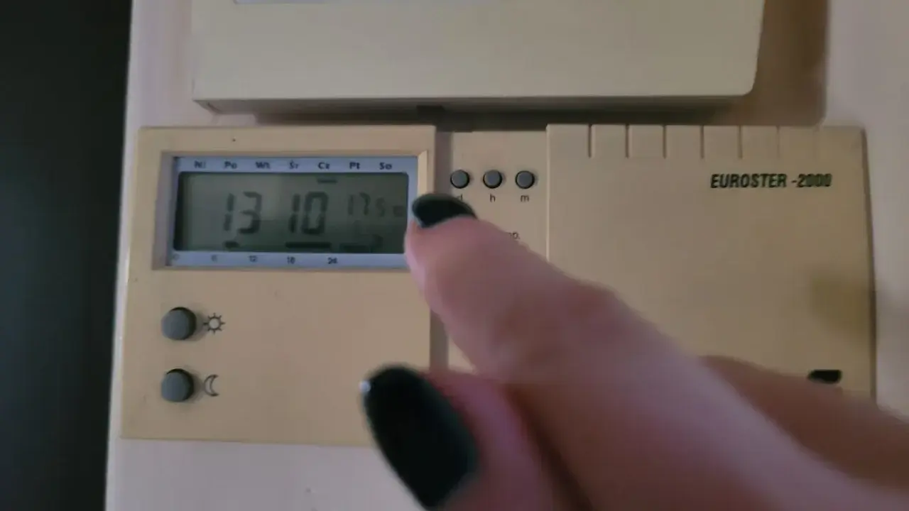Dłoń z czarnym lakierem na paznokciach dotyka termostatu, sterowanie piecem gazowym. Na wyświetlaczu 13:10 i 17.5°C.