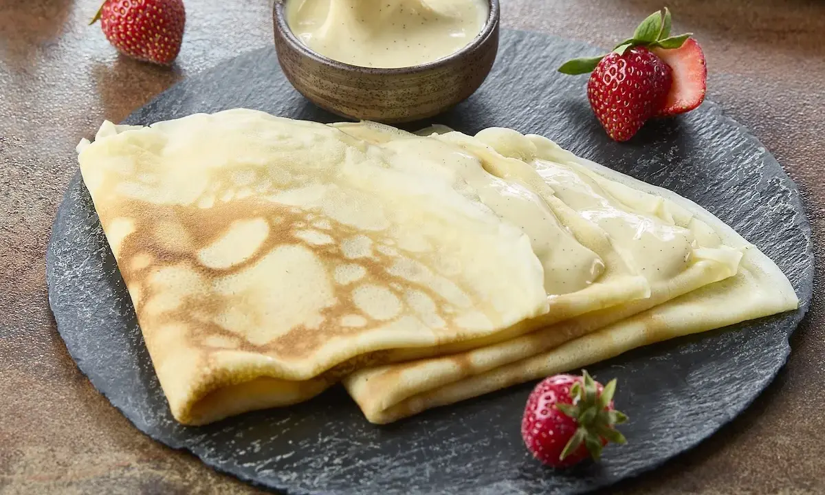 Délicieuses crêpes de riz garnies de crème vanillée, accompagnées de fraises fraîches. Un délice gourmand.