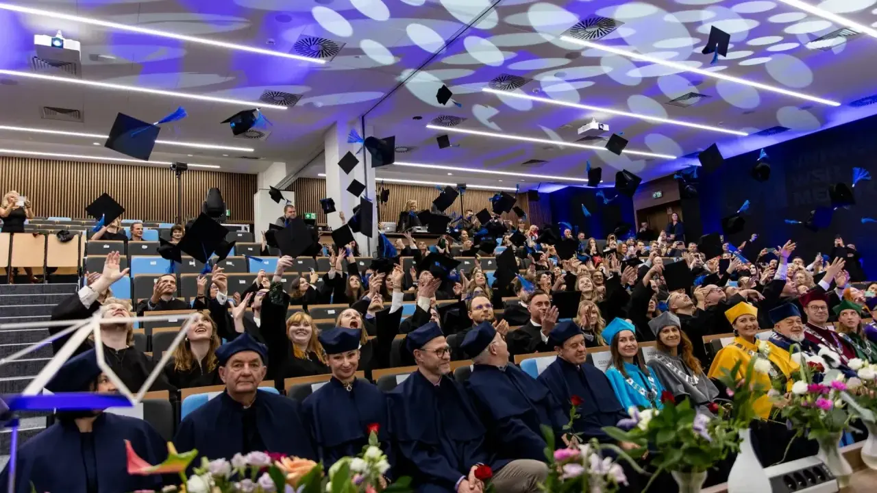Absolwenci rzucają birety w powietrze podczas uroczystości. Radość i duma po ukończeniu studiów prawniczych w Gdańsku.