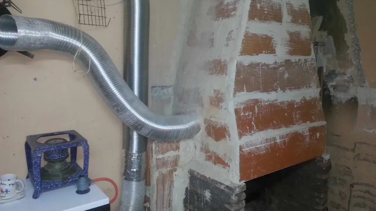 Instalación de tubos flexibles para estufa de leña, conectando a la chimenea de ladrillo.