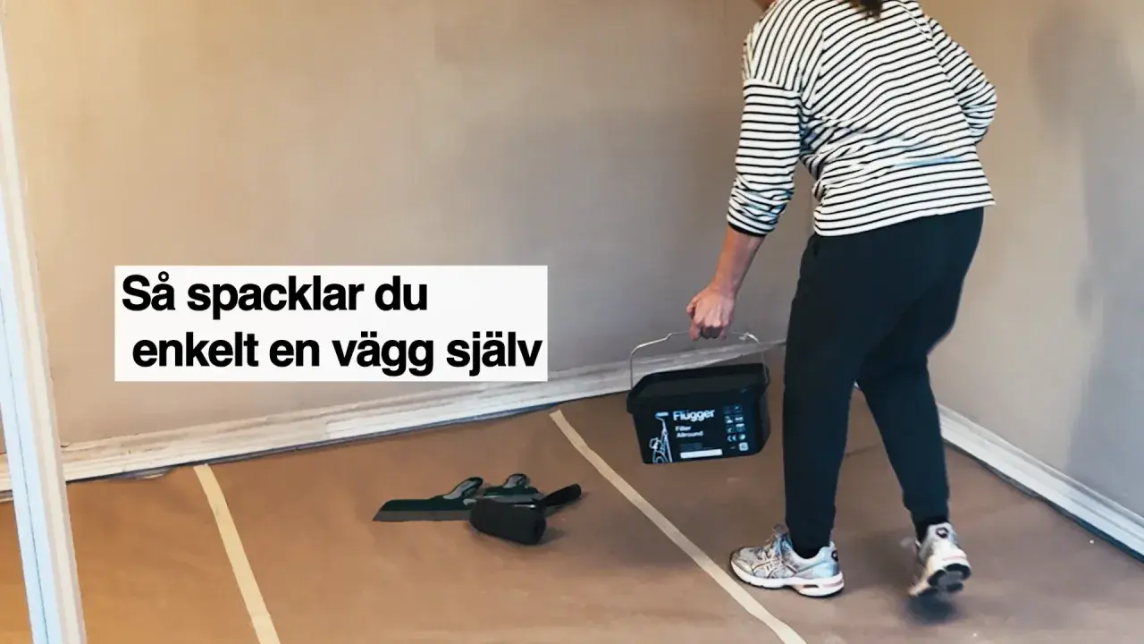 Person med hink med spackel och verktyg för att slipa och jämna ut en vägg.