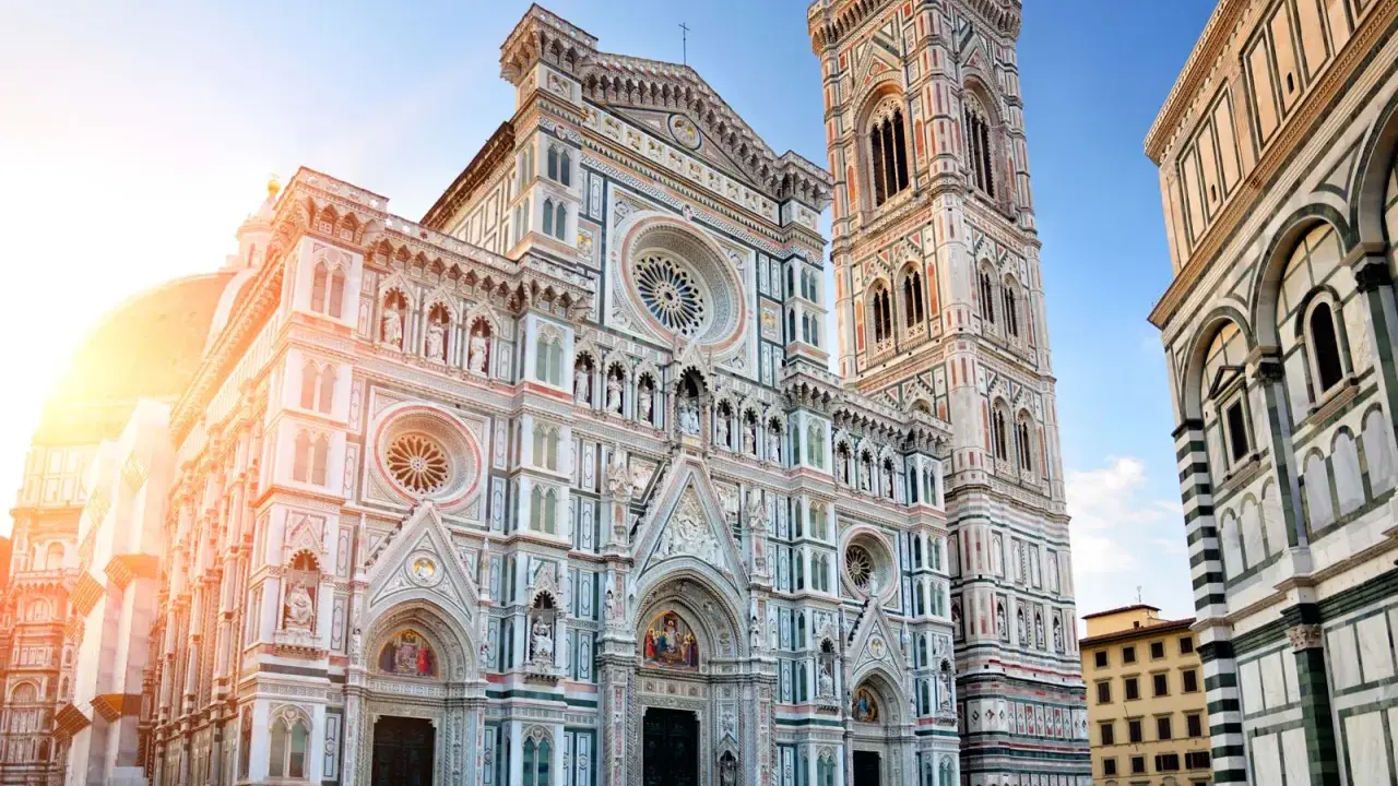 La majestueuse coupole de Florence, le Duomo, se dresse fièrement sous un ciel bleu, baignée par les rayons du soleil.