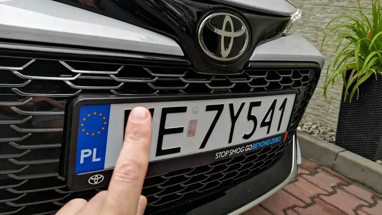 Palec wskazujący na tablicy rejestracyjnej samochodu. Czy to zgubiona rejestracja?