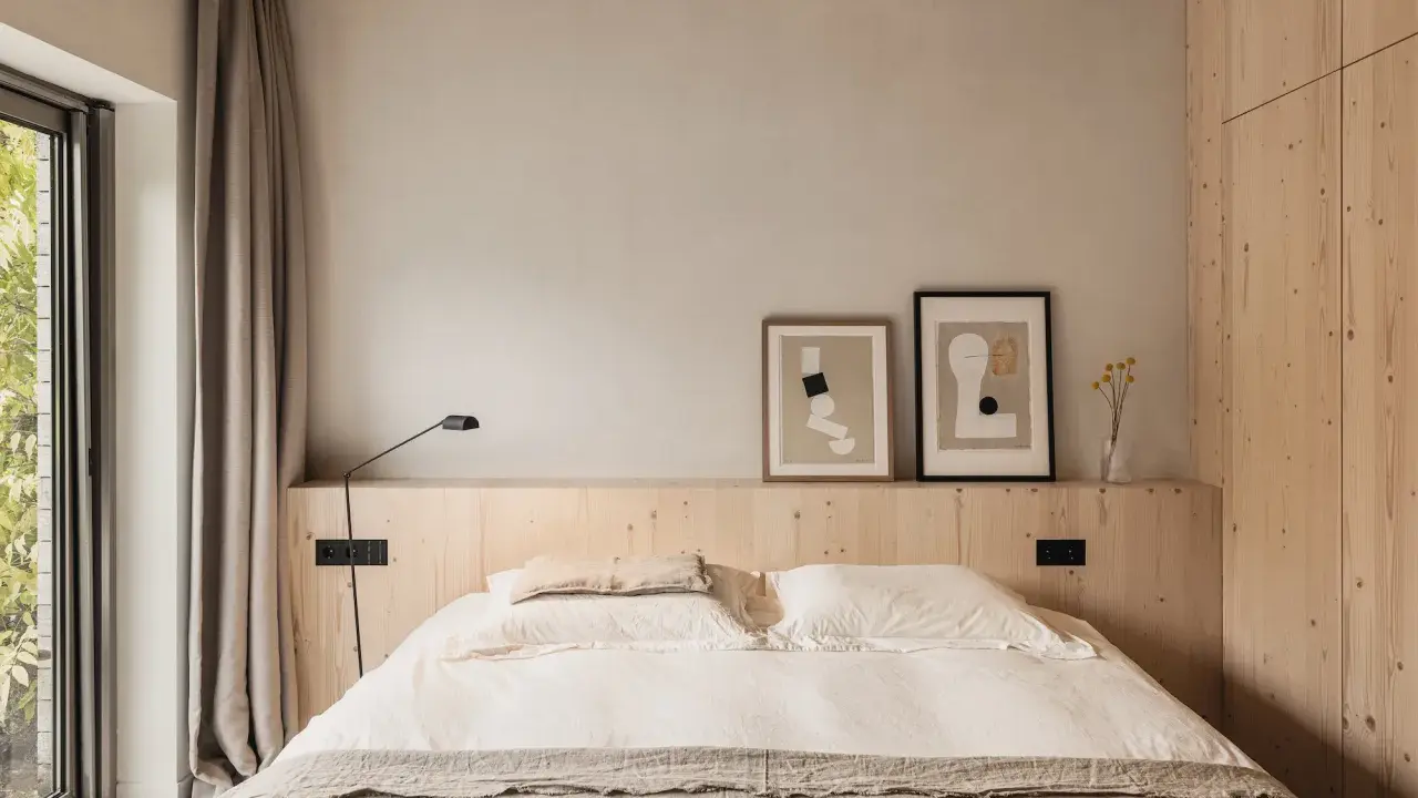 Acogedor dormitorio sin cabecero, con cama de lino, arte abstracto y armario de madera.
