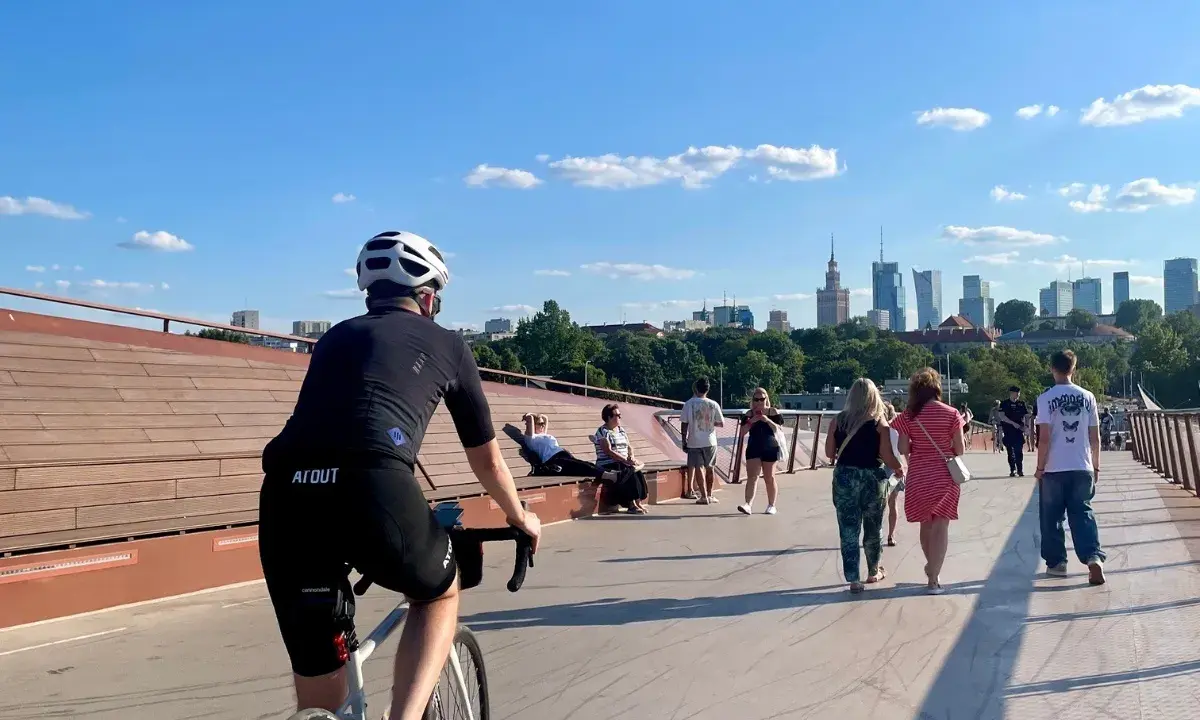 Rowerzysta na moście w Warszawie, w tle panorama miasta. Idealne miejsce na odkrywanie tras rowerowych Warszawa i okolice.