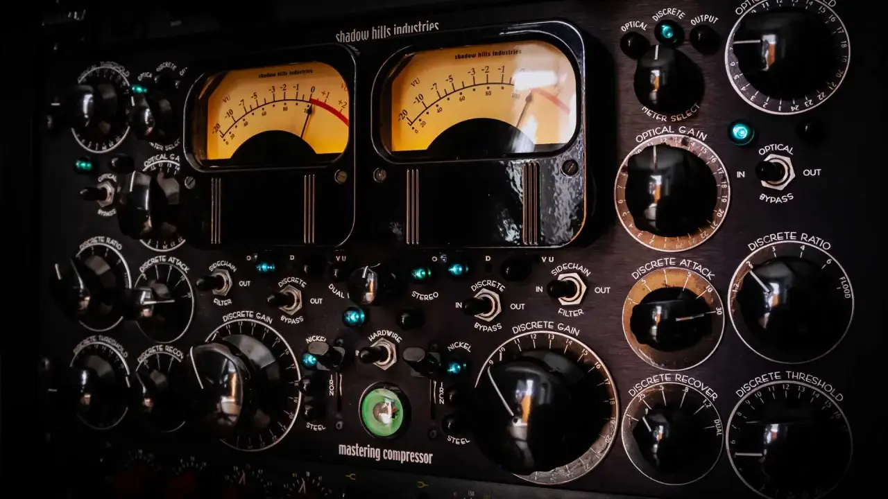 Panneau de compresseur mastering avec deux VU-mètres lumineux. Apprenez comment utiliser un compresseur en ajustant les nombreux boutons et sélecteurs.