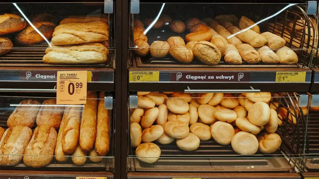 Różnorodne bułki i bagietki na półkach sklepowych. Idealne na śniadanie, choć warto sprawdzić ich kcal.
