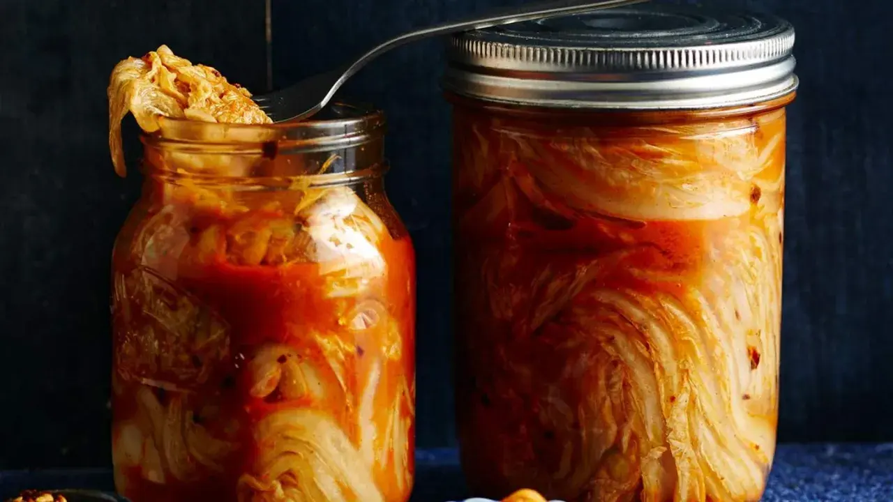 Zwei Gläser mit fermentiertem Chinakohl, bereit für das authentische kimchi rezept original. Ein Löffel ragt aus dem linken Glas.