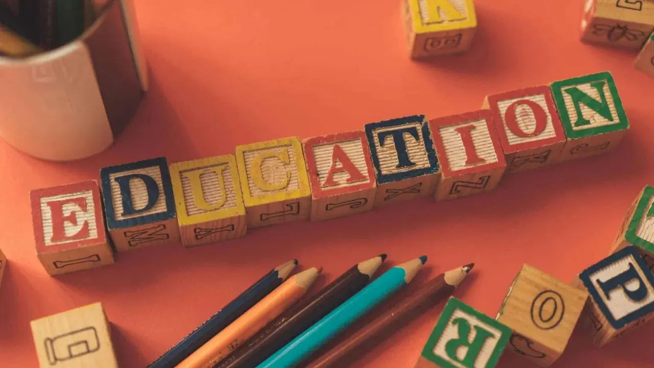 Klocki z literami tworzą napis EDUCATION. Obok leżą kredki i inne klocki, idealne do nauki tekstów po angielsku B2.