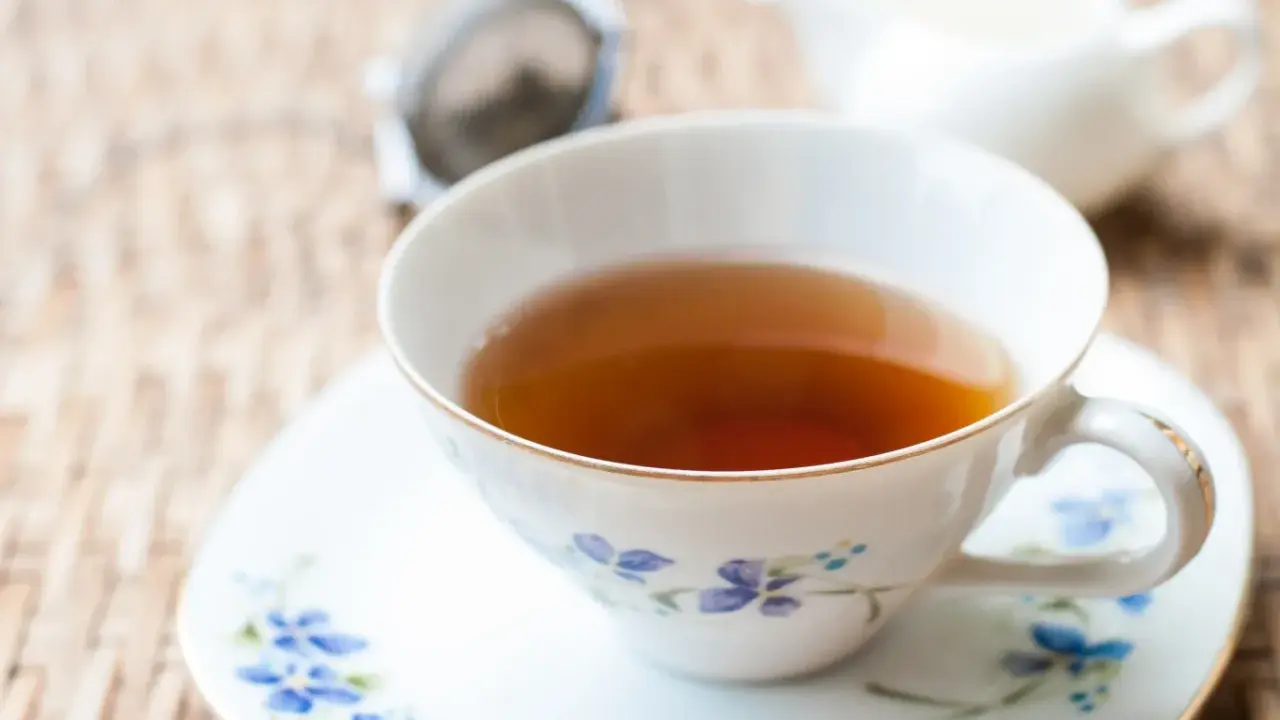 Aromaticzna herbata Earl Grey, znana ze swoich właściwości pobudzających i relaksujących, w eleganckiej filiżance z niebieskimi kwiatami.