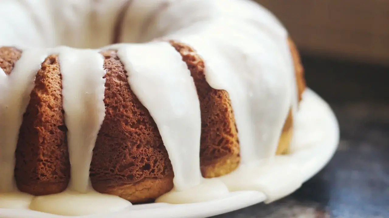 Gâteau moulé, doré, nappé d'un glaçage blanc crémeux. Une invitation à découvrir comment faire du fondant blanc.