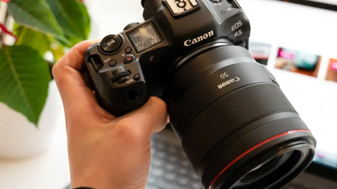 Dłoń trzyma aparat Canon R5 z obiektywem 50mm. Trwa test możliwości sprzętu.