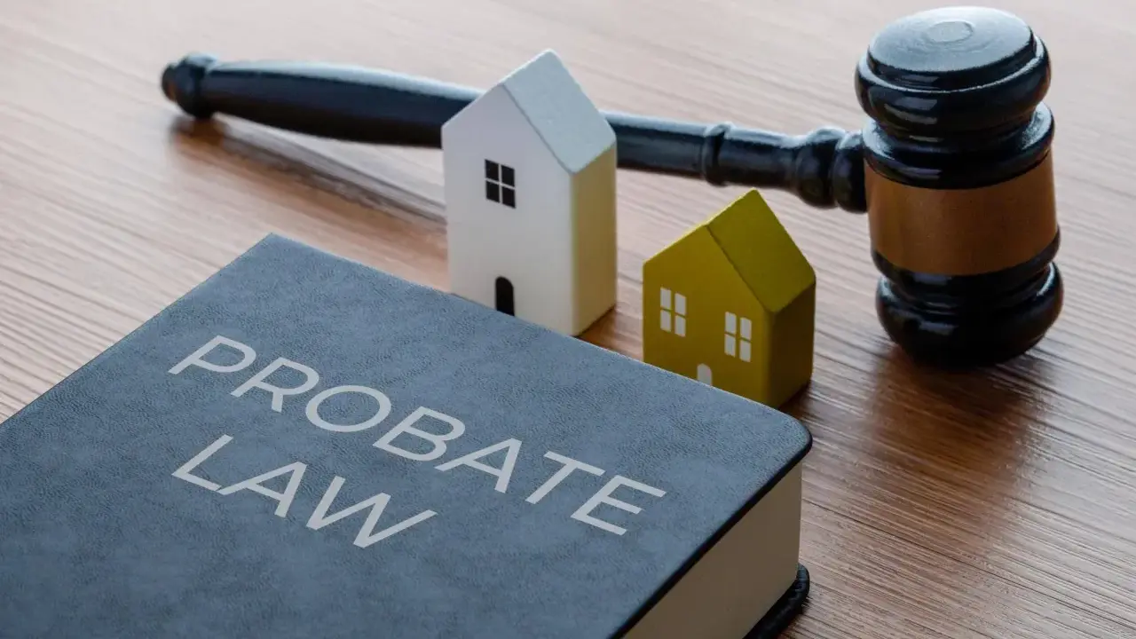 Księga "Probate Law", młotek sędziowski i dwa domki symbolizują dziedziczenie. Dowiedz się, ile procent zachowek przysługuje.