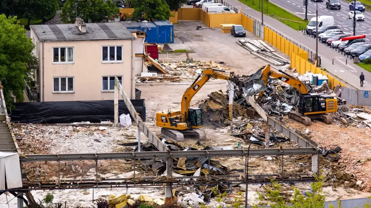 Dwa koparki pracują przy wyburzaniu budynku. Szacowany koszt wyburzenia domu 100m2 może być wysoki.