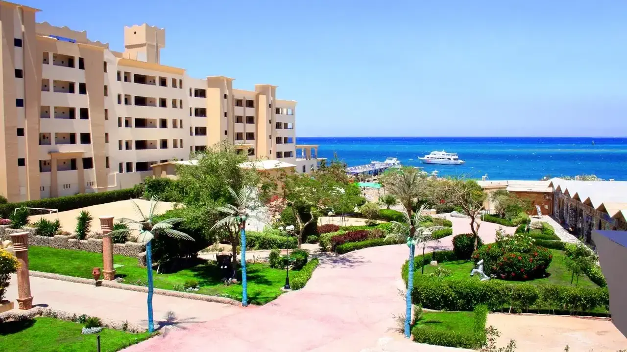 Piękny widok na **King Tut Resort** z basenem, palmami i morzem w tle.