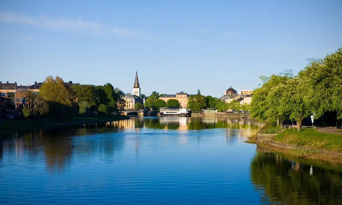 Vacker stad vid vattnet med kyrktorn och gröna träd. Tänk dig att bo på ett mysigt vandrarhem i Torsby och vakna till denna vy.